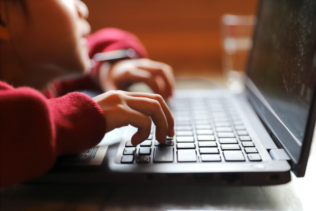 About us. Young boy typing on laptop.